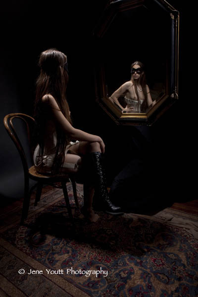 corseted female wearing blk mask & boots